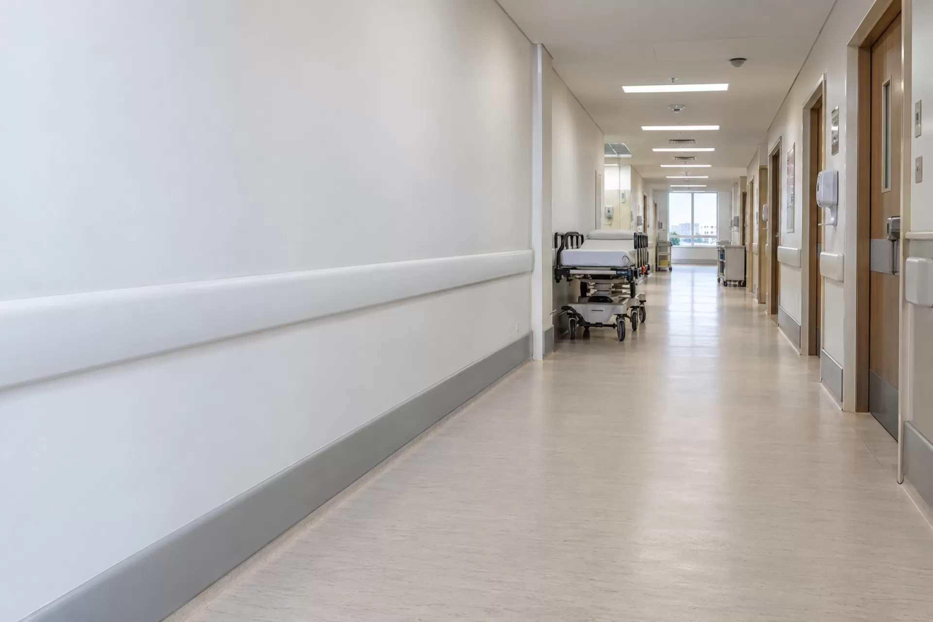 Corredor de hospital com faixa protetora de parede em PVC instalada ao longo da parede e maca ao fundo