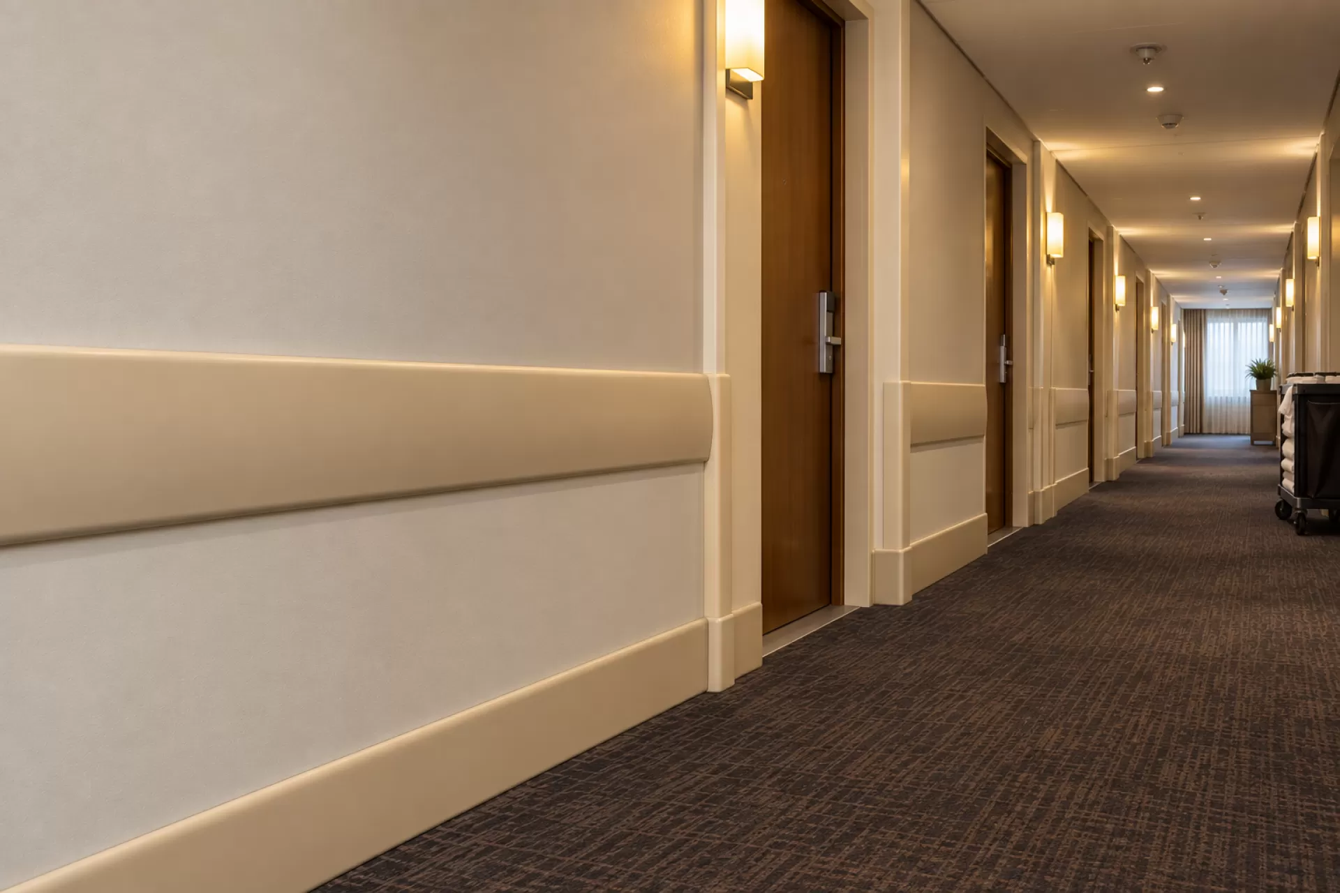 Corredor de andar de hotel com a parede preservada e carrinho de serviço ao fundo
