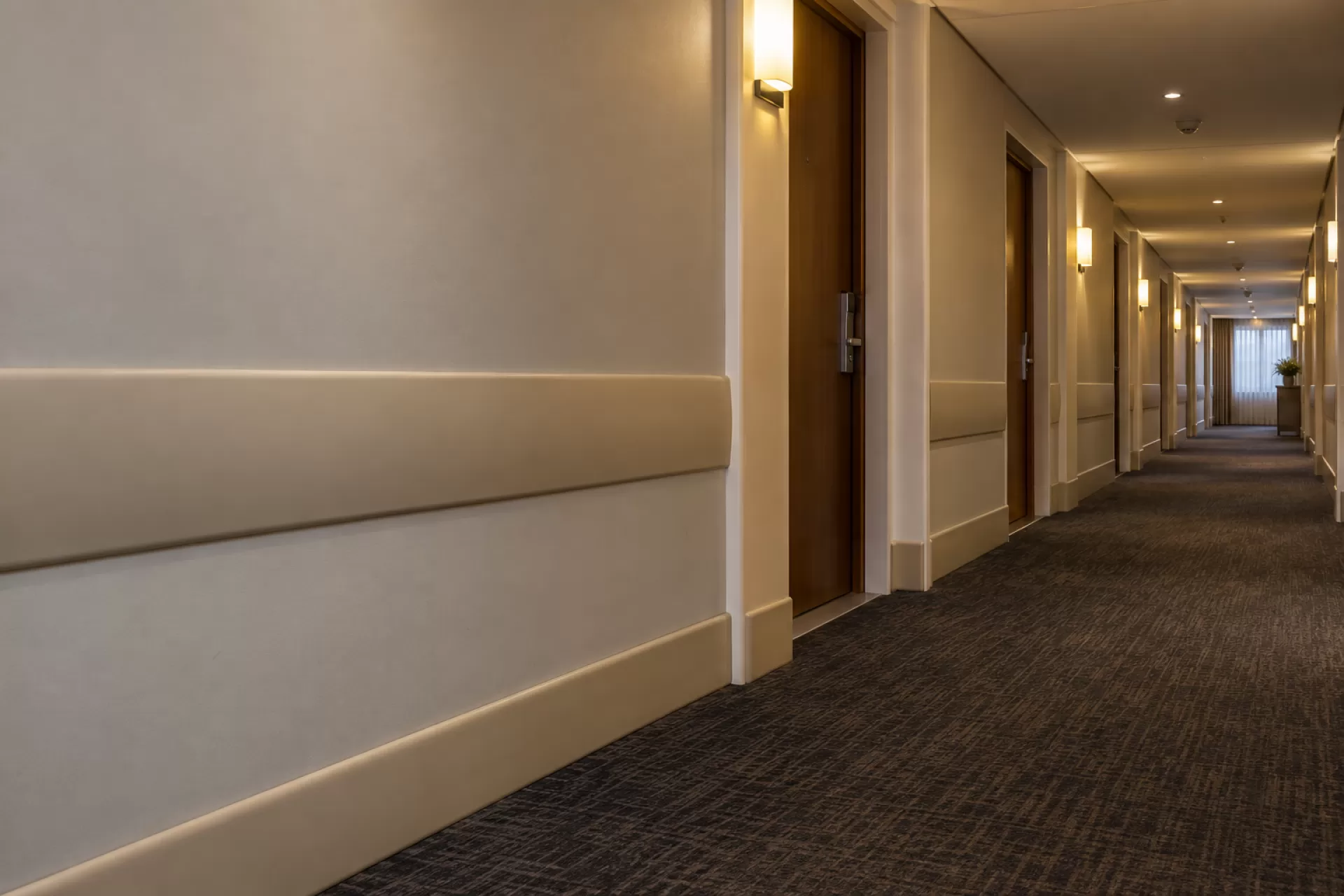 Corredor de andar de hotel com carpete e perfil de proteção instalado na parede